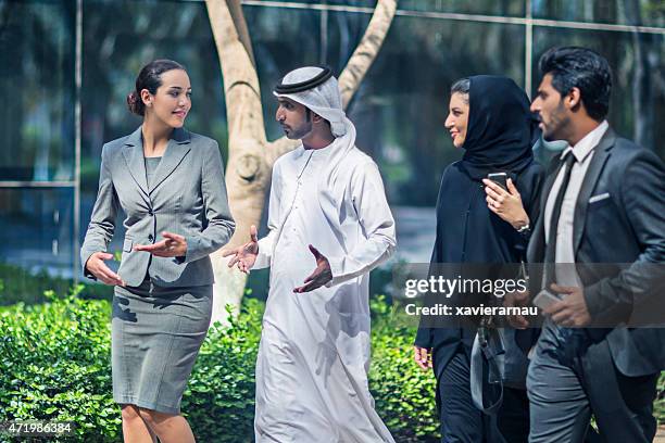 uomini d'affari mediorientali parlare in strada - emirati at work foto e immagini stock