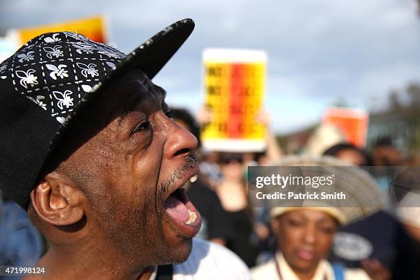 Man tears up as protestors march on the street at North Ave., and Pennsylvania Ave., in West Baltimore a day after Baltimore authorities released a...