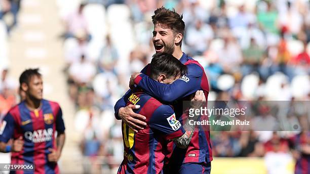 Gerard Pique of FC Barcelona celebrates with his team-mate Lionel Messi as he scored the fifth goal during the La Liga match between Cordoba CF and...