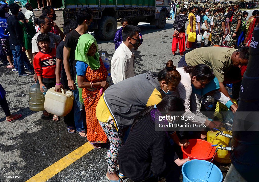 People in queue to take water from a temporary shelter at...