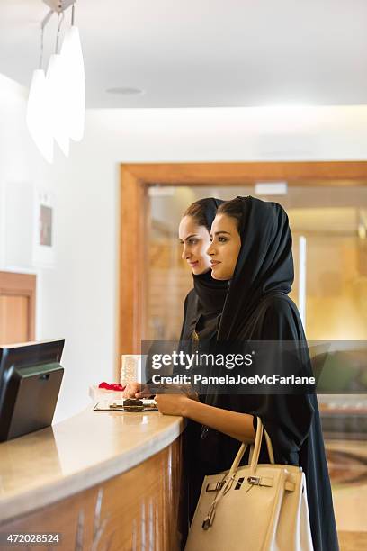 traditionell gekleideten nahen osten frauen, die beim check-in am empfang - dubai spa stock-fotos und bilder