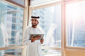 Arab businessman using digital tablet in Dubai office.