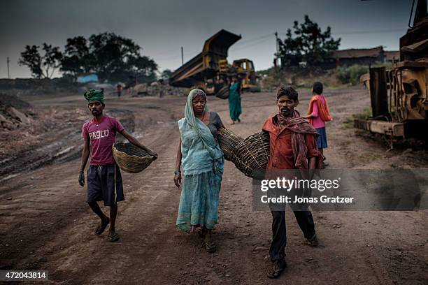 Group of coal mine workers are carrying their baskets and walking down the road in Jharia. Jharia in India's eastern Jharkand state is literally in...