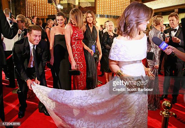 Karl Stefanovic bends down to adjust the dress of Lisa Wilkinson as Jesinta Campbell looks on at the 57th Annual Logie Awards at Crown Palladium on...
