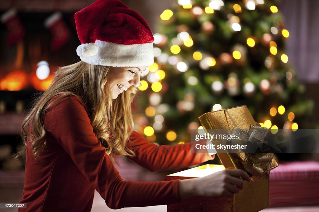 Cheerful woman opening Christmas presents.