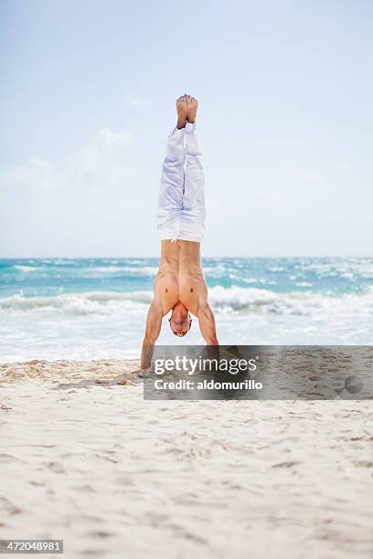 young fit man doing a handstand at the beach - handstand beach stock pictures, royalty-free photos & images