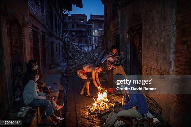 Members of the Tsayana family warm themselves next to a fire outside their damaged home house on May 3, 2015 in Bhaktapur, Nepal. A major 7.8...