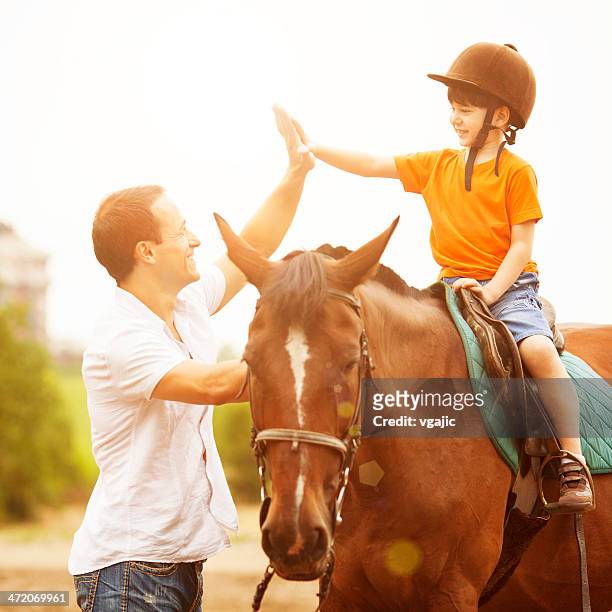 father support son riding horse outdoors. - dressage stock pictures, royalty-free photos & images
