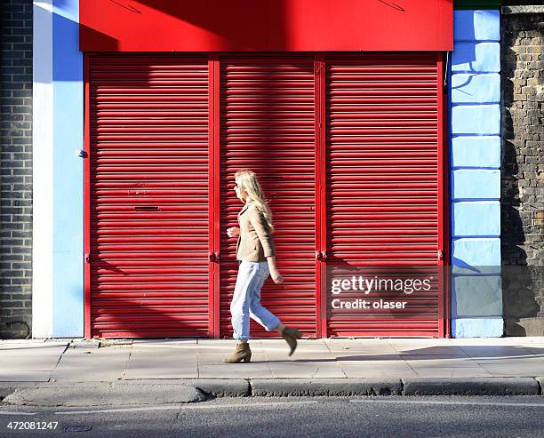 woman, brightly lit in the morning, walking early london street - shop shutter stock pictures, royalty-free photos & images