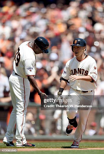 Nori Aoki of the San Francisco Giants is congratulated by third base coach Roberto Kelly after Aoki hit a lead-off solo home run against the Los...