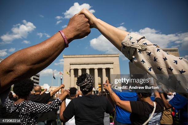 People hold hands during a rally lead by faith leaders in front of city hall calling for justice in response to the death of Freddie Gray on May 3,...