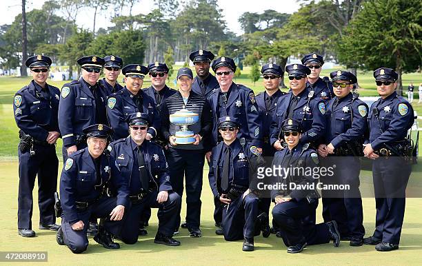 Rory McIlroy of Northern Ireland holds the Walter Hagen Cup with a group of San Francisco Police Officers after his win in the final match of the...