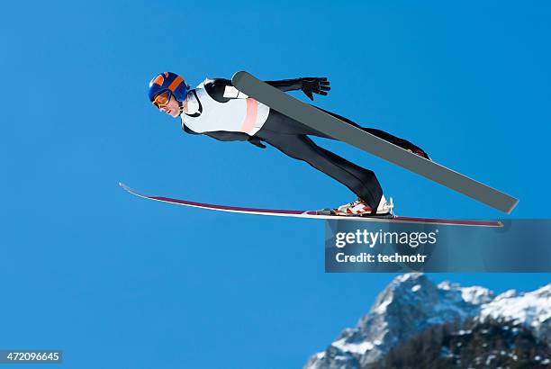 atleta de salto de esqui em acção contra o céu azul - salto de esqui imagens e fotografias de stock