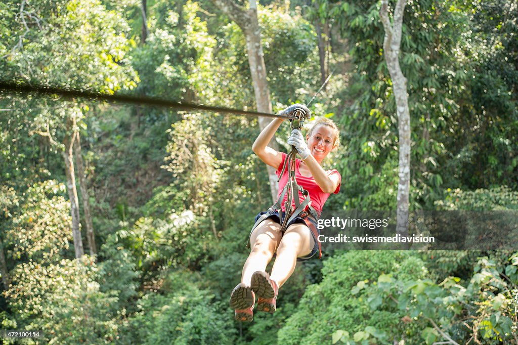 Aventure femme heureuse sur une tyrolienne en traversant la jungle