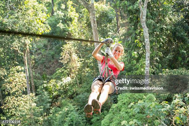 happy adventurous woman on a zip-line crossing the jungle - zipline stock pictures, royalty-free photos & images