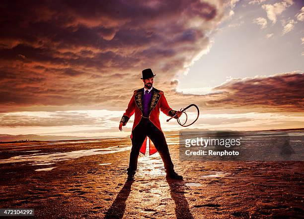 circus ring master in a dramatic desert setting - whip stock pictures, royalty-free photos & images