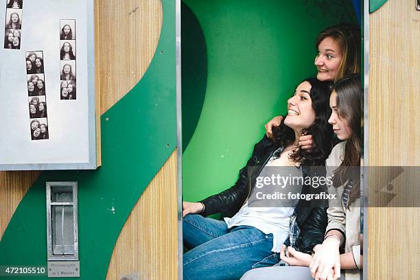 three teenager girls together in photo booth making faces - photo booth stockfoto's en -beelden