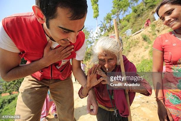 Nepalese elder women salutes a Turkish Red Crescent member as he carried a package to help her during Turkish Red Crescent dispatch foods, blankets...