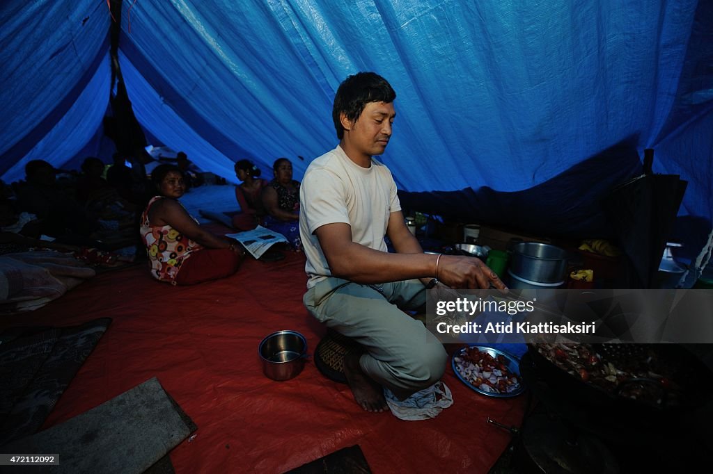 Nepalese man cooks dinner in his temporary tent after they...