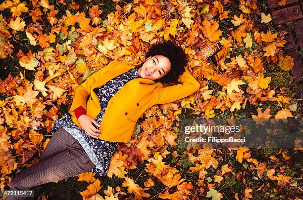 young woman lying down on yellow leaves - beautiful woman fall stock pictures, royalty-free photos & images