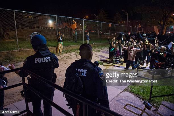 Protestors sit with their hands up moments before being arrested at the Latrobe Homes after the 10 p.m. Curfew as people march around the city in...