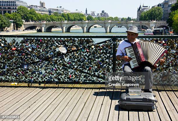 mann spielt in der nähe der liebe vorhängeschlösser - le pont des arts and the love padlocks in paris stock-fotos und bilder