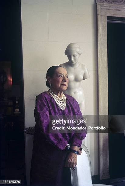 "Polish entrepreneur Helena Rubinstein, born Chaja Rubinstein, poses in her villa wearing a lilac dress and pearls necklace. New York , April 1964. "