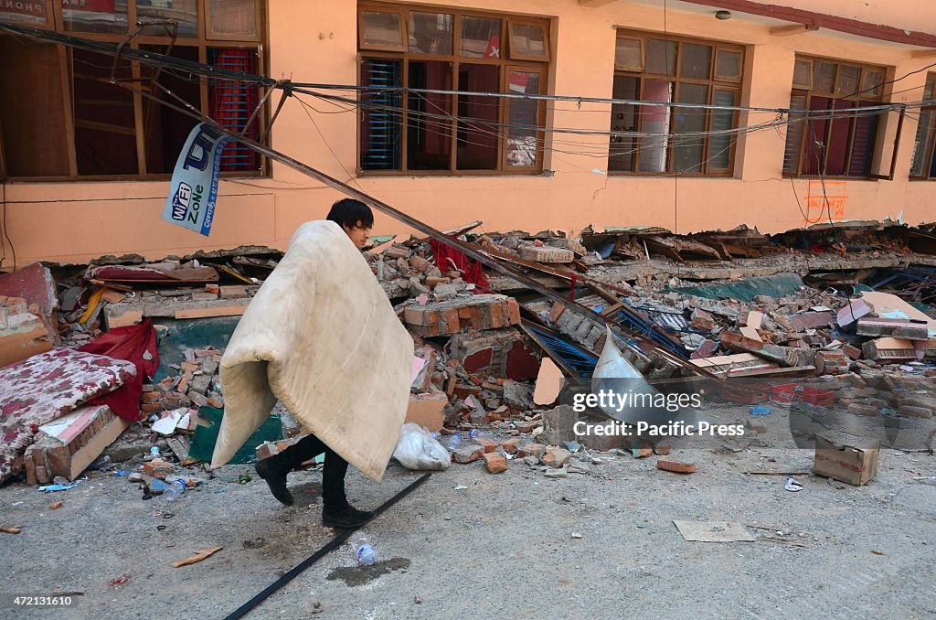 A youth carrying clothe near in a debris of houses at New...