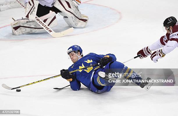 Forward Filip Forsberg of Sweden and defender Kristaps Sotnieks of Latvia vie for the puck during the group A preliminary round ice hockey match...