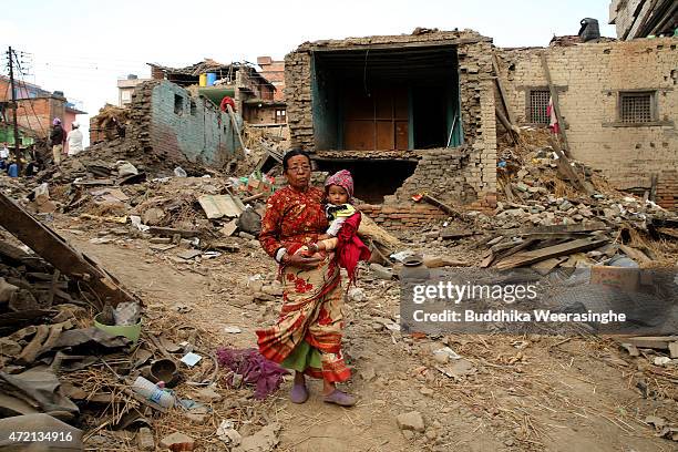 An elderly Nepalese woman carries her 4-year-old granddaughter, Denisha, as they walk among the rubble of collapsed buildings at Harisidaahi village...