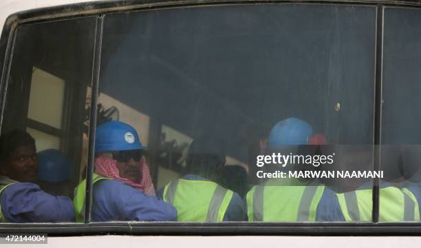 Foreign laborers working on the construction site of the al-Wakrah football stadium, one of the Qatar's 2022 World Cup stadiums, sit in a bus as they...