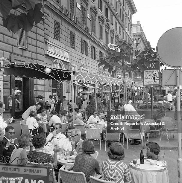 View of the pavement on via Veneto with people sitting at the tables of the well-known 'Cafè de Paris'. Rome, 1958