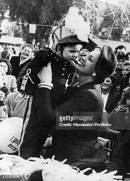 "French model Begum Om Habibeh Aga Khan , fourth wife of Imam of the Nizari Ismaili community Aga Khan III, hugging a child dressed as a gendarme. Le...