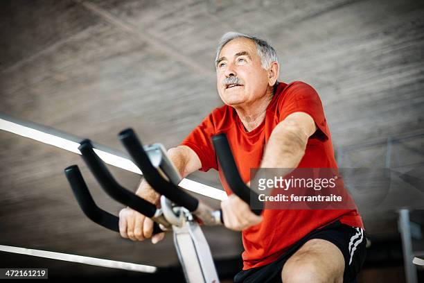 senior man on exercising bicycle - peloton stock pictures, royalty-free photos & images