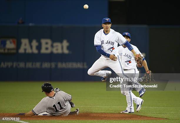 Ryan Goins of the Toronto Blue Jays turns a double play in the fourth inning during MLB game action as Brett Gardner of the New York Yankees slides...