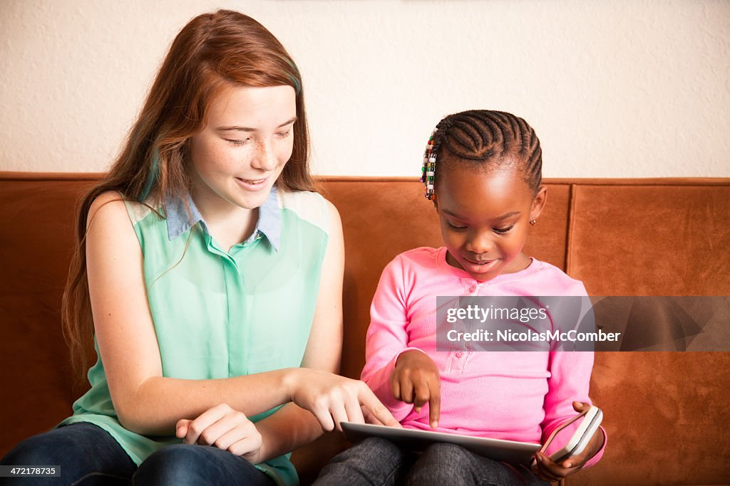 Baby sitter playing with preschooler using tablet mobile phone