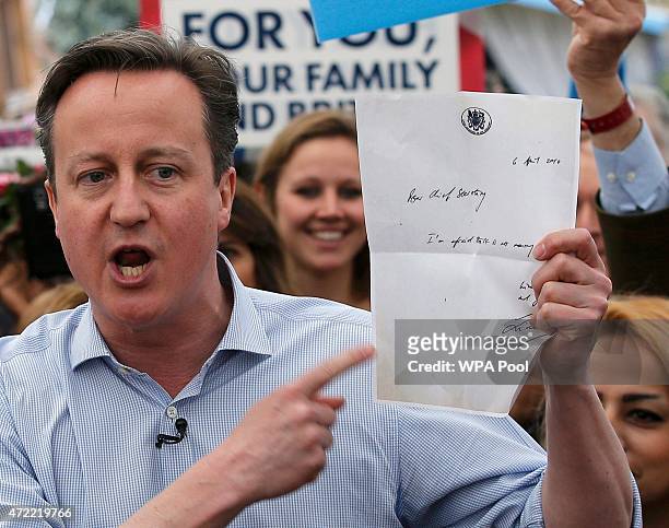 British Prime Minister David Cameron holds up a letter from former Labour Treasury Minister Liam Byrne in 2010, which reads "Im afraid there is no...