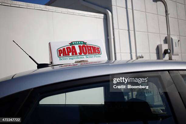 Papa John's International Inc. Sign sits attached to the roof of a delivery vehicle outside of a restaurant in Louisville, Kentucky, U.S., on Friday,...