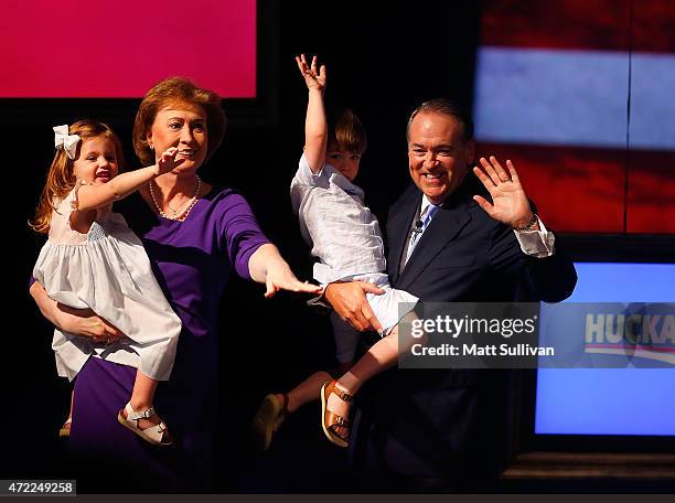 Former Arkansas Governor Mike Huckabee and his wife, Janet, hold their grandchildren Scarlet Sanders and Chandler Huckabee after announcing his...