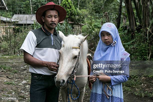 Year old Ridwan Sururi posses for a portrait with his daughter Indriani Fatmawati and Luna, a horse used as mobile library on May 5, 2015 in Serang...