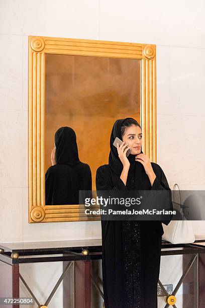 アバヤ中東の女性の携帯電話で話しているホテル - パウダールーム　女性 ストックフォトと画像