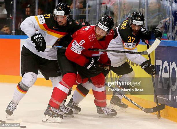 Timo Helbling of Switzerland and Nicolas Krammer and Patrick Reimer of Germany battle for the puck during the IIHF World Championship group A match...