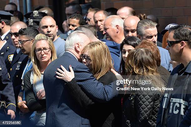 Police Commissioner Bill Bratton hugs family and police line up as the body of police officer Brian Moore leaves Jamaica Hospital. He was shot in the...
