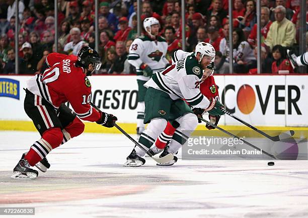 Kyle Brodziak of the Minnesota Wild advances the puck between Patrick Sharp and Antoine Vermette of the Chicago Blackhawks in Game Two of the Western...