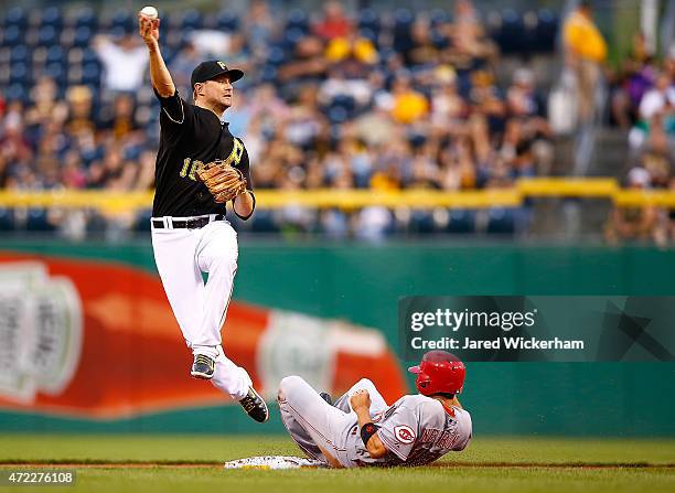 Jordy Mercer of the Pittsurgh Pirates turns the double play over Kristopher Negron of the Cincinnati Reds in the second inning during the game at PNC...