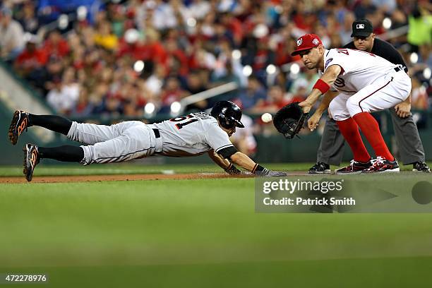 Ichiro Suzuki of the Miami Marlins slides back into first base in the second inning as Ryan Zimmerman of the Washington Nationals stands on the base...
