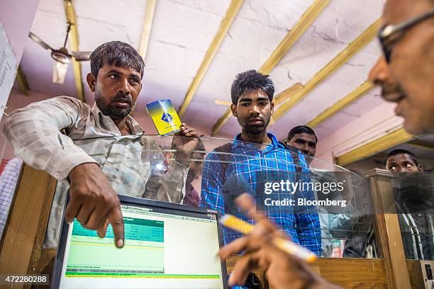 An employee serves customers inside a branch of Gramin Bank of Aryavat , sponsored by Bank of India, in the village of Khurana, Uttar Pradesh, India,...