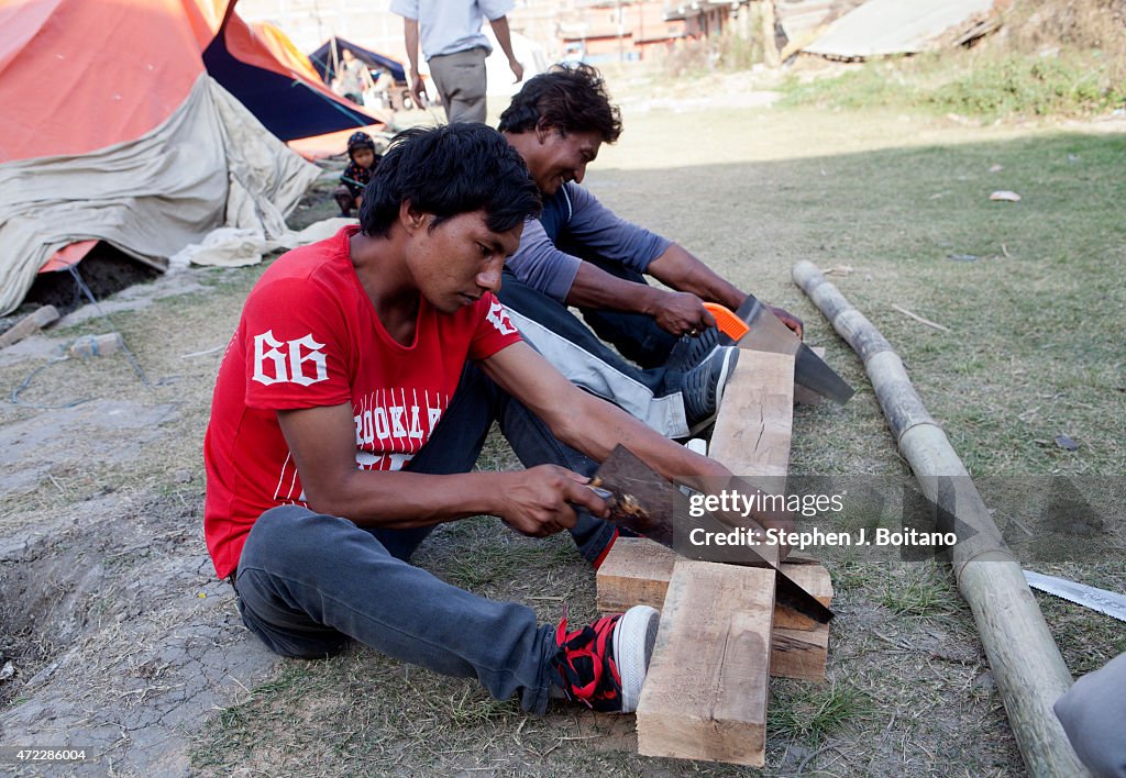 Men cut wood for toilets at an IDP camp in Bhaktapur. A...