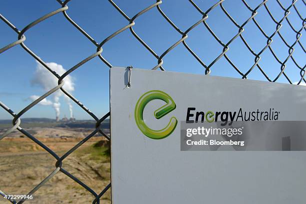 The logo of EnergyAustralia Holdings Ltd., a unit of CLP Holdings Ltd., is displayed on a gate as steam billows from the company's Yallourn...