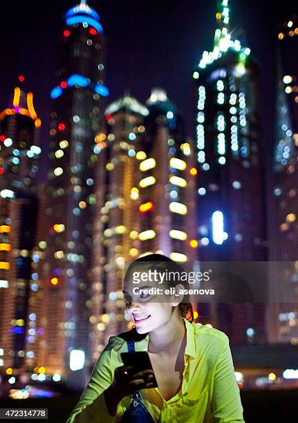 woman texting on the smart phone in dubai marina. - dubai taxi stock pictures, royalty-free photos & images
